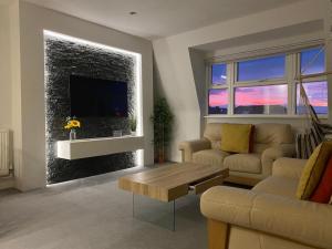 a living room with a couch and a tv on a wall at Coastline Retreats - Newly Refurbished Town centre, Close to beach, Large Jet bath with TV, Netflix, swing and we pay parking in Bournemouth