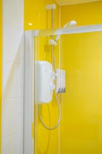 een douche in een badkamer met een gele muur bij Lovely Studio Serviced Apartment Sheffield City Centre - Netflix, WiFi, Digital TV in Sheffield