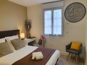 a bedroom with a bed and a clock on the wall at Hôtel et Chambres d'hôtes Les Mureaux - Les chambres de la Marina in Les Mureaux
