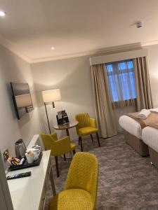 ニューカッスル・アポン・タインにあるカレドニアン ホテルのベッド、テーブル、椅子が備わるホテルルームです。