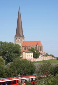 una iglesia con un campanario y un tren delante de él en Ursprung Apartments, en Rostock
