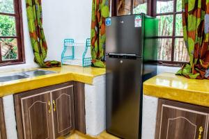 La cuisine est équipée d'un réfrigérateur et d'un évier. dans l'établissement Etana Cottage, à Kakamega