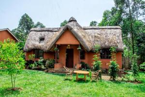 a house with a thatched roof with a table in front at Etana Cottage in Kakamega
