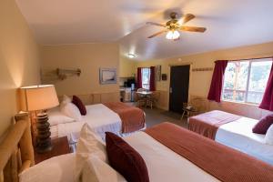 um quarto de hotel com 3 camas e uma ventoinha de tecto em McKinley Creekside Cabins em McKinley Park