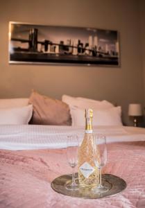 a bottle of champagne and two glasses on a bed at Apartament Podcienie z tarasem Bielsko-Biała Old Town in Bielsko-Biała