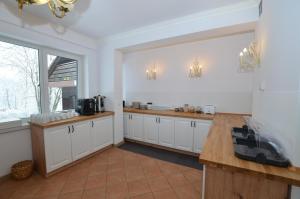 a kitchen with white cabinets and a large window at Villa Słonecznego Wzgórza in Zakopane