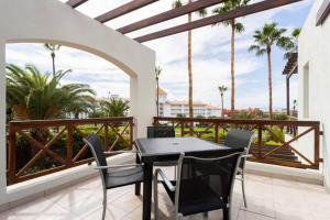 een zwarte tafel en stoelen op een balkon met palmbomen bij Costa Adeje Luxury Mango in Adeje