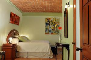 - une chambre avec un lit et une table avec un vase dans l'établissement Marhialja Hotel Boutique, à Oaxaca