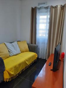 a living room with a yellow couch and a tv at Mar House Apartments in Praia