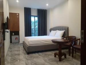 Schlafzimmer mit einem Bett, einem Tisch und einem Fenster in der Unterkunft PEACE HOTEL in Vũng Tàu