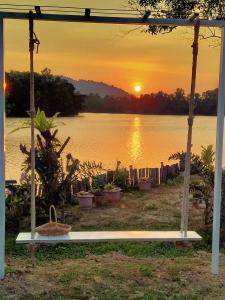 a swing with a view of a lake at sunset at Khum Thong Resort in Takua Pa