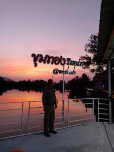 a man standing in front of a sign in front of a lake at Khum Thong Resort in Takua Pa