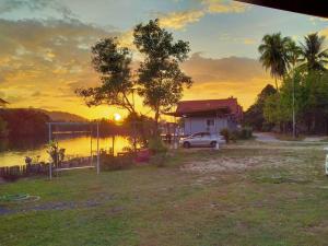 um carro estacionado em frente a uma casa com o pôr do sol em Khum Thong Resort em Takua Pa