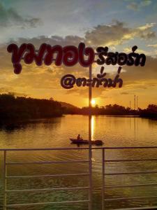 a sign for a boat on a river at sunset at Khum Thong Resort in Takua Pa