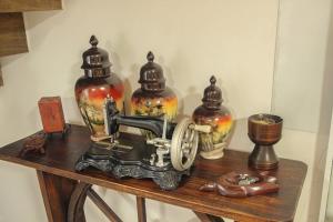 una mesa con una máquina de coser y tres jarrones en ella en Casa Rebello - Pousada, en Itajaí