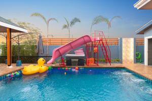 una piscina con un tobogán y un pato de goma en una casa en หมุนเงินหมุนทองพูลวิลล่า Mhunngen Mhunthong Pool Villa en Cha Am