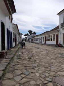 two people walking down a cobblestone street with buildings at Casa térrea in Paraty