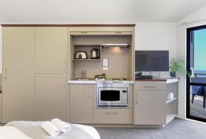 a kitchen with white cabinets and a microwave at Castaways Resort in Waiuku