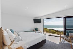 a bedroom with a bed and a view of the ocean at Castaways Resort in Waiuku