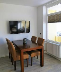 a dining room table with chairs and a television on a wall at Vier Jahreszeiten 2-53 in Großenbrode