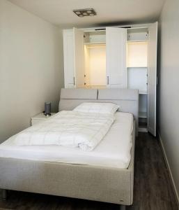 uma cama branca num quarto com duas janelas em Vier Jahreszeiten 2-53 em Grossenbrode