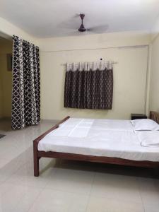 a bedroom with a bed in a room with curtains at Vidhara Rooms in Trivandrum