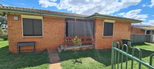 a brick house with a fence in front of it at Kubo House in Dubbo