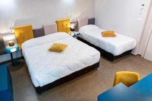two beds with yellow pillows in a room at Hotel Eubea in Reggio Calabria