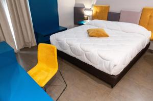 a bedroom with a white bed and a yellow chair at Hotel Eubea in Reggio di Calabria