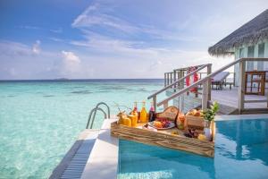 a table with drinks next to a swimming pool at Sun Siyam Iru Veli Premium All Inclusive in Dhaalu Atoll