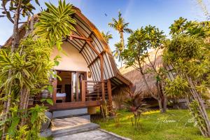 a small house with a thatched roof in a forest at Oceans 5 Dive Resort in Gili Air