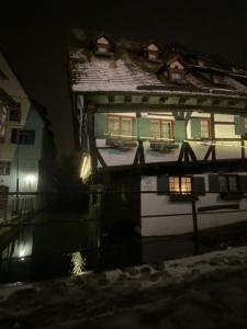 a house with a reflection in the water at night at Hotel Schiefes Haus in Ulm
