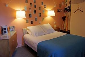 Un dormitorio con una cama con dos luces. en Hotel Auberge des Remparts, en Laval