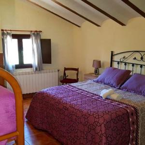 a bedroom with a bed with purple sheets and a window at Casa del Águila Dorada in Riópar Viejo