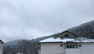 Un bâtiment blanc avec de la neige sur le toit dans l'établissement Cocooning in a Lovely Mountain suite - One, à Azuga