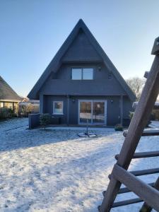 uma casa com um telhado de gambrel na neve em Fräulein Emma Lotta em Kronsgaard