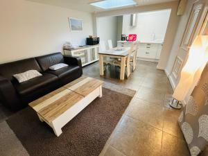 Una sala de estar con un sofá negro y una mesa. en Petite Maison Andernos, en Andernos-les-Bains