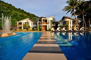 a swimming pool in front of a house with a fountain at Infinity Resort in Puerto Galera