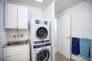a kitchen with a washing machine and a sink at Heart of Airlie Beach Apartment in Airlie Beach
