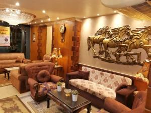 sala de estar con sofá y un caballo en la pared en City Center Hotel Beni Suef, en Banī ‘Aţīyah