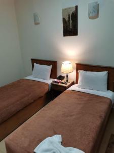 una habitación de hotel con 2 camas y una lámpara en una mesa en City Center Hotel Beni Suef en Banī ‘Aţīyah