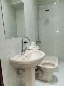 a white bathroom with a sink and a toilet at City Center Hotel Beni Suef in Banī ‘Aţīyah