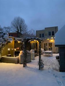 un patio cubierto de nieve con cenador con luces en B & B Simme Zimme, en Brasschaat