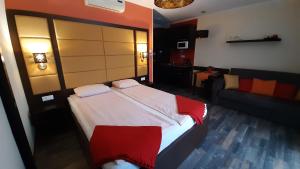 um quarto com uma cama grande e um sofá em 4 ÁSZ Deluxe Apartman em Gyula