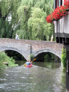 Ein Mann im Kajak auf einem Fluss unter einer Brücke. in der Unterkunft Hotel Schiefes Haus in Ulm