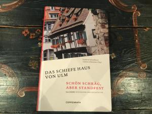 烏爾姆的住宿－Hotel Schiefes Haus，一本书,上面有房子的照片