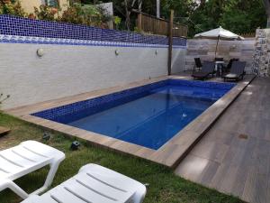 a swimming pool with two chairs and an umbrella at Recanto do Angelo in Praia do Forte