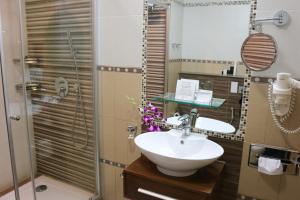 a bathroom with a sink, mirror, and tub at Elite Crystal Hotel in Manama