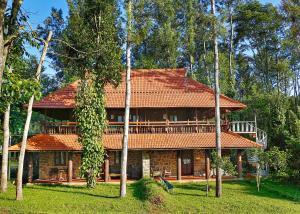 a house with an orange tile roof and trees at Elephant Valley Eco Farm Hotel in Kodaikānāl