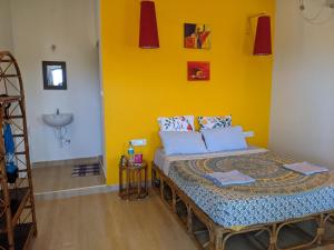 a bedroom with a bed and a yellow wall at Blue Moon Guest House in Mahabalipuram